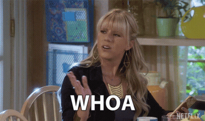 A Woman Sitting At A Table Says Whoa GIF