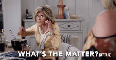 A Woman Sitting At A Table Talking On A Cell Phone With The Words What 'S The Matter Netflix Behind Her GIF
