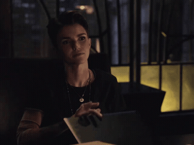 A Woman Sitting At A Table With A Blue Folder In Front Of Her GIF