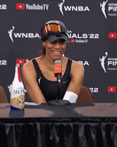 A Woman Sitting At A Table With A Bottle Of Bud Light Ultra On It GIF