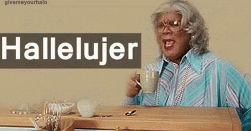 A Woman Sitting At A Table With A Cup Of Coffee And A Sign That Says Hallelujer On It GIF