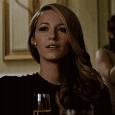 A Woman Sitting At A Table With A Glass Of Champagne GIF