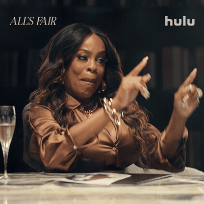 A Woman Sitting At A Table With A Glass Of Champagne And Hulu Written On The Bottom GIF