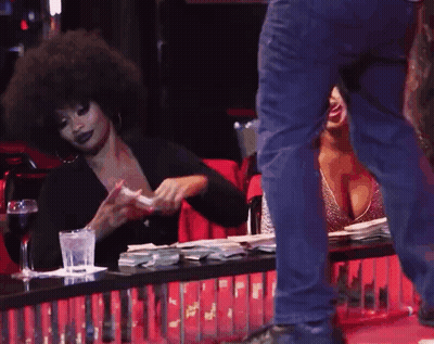 A Woman Sitting At A Table With A Glass Of Water And A Man Standing Behind Her GIF