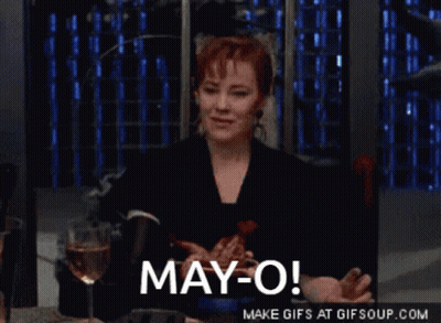 A Woman Sitting At A Table With A Glass Of Wine And The Words May-O GIF