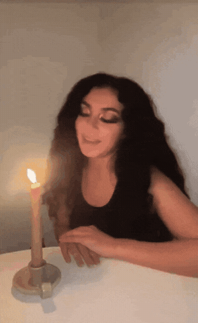 A Woman Sitting At A Table With A Lit Candle GIF