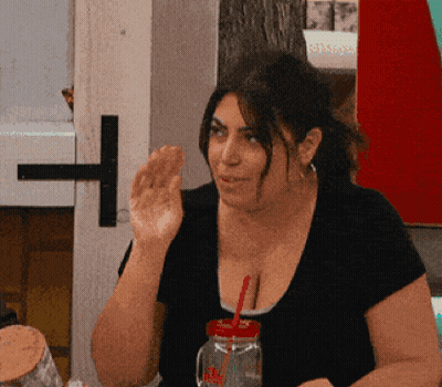 A Woman Sitting At A Table With A Mason Jar With A Red Straw GIF