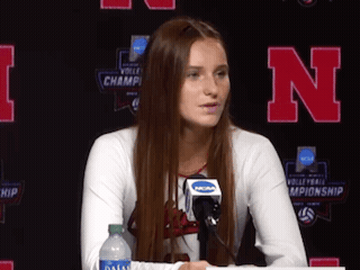 A Woman Sitting At A Table With A Microphone And A Bottle Of Water . GIF