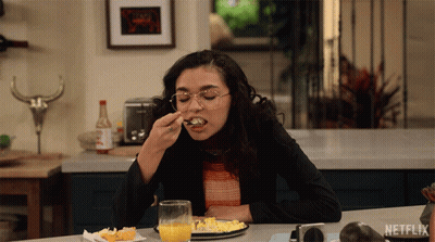 A Woman Sitting At A Table With A Plate Of Food And A Glass Of Orange Juice With Netflix Written On The Bottom GIF