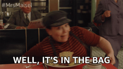 A Woman Sitting At A Table With A Plate Of Food And The Words Well It 'S In The Bag Above Her GIF