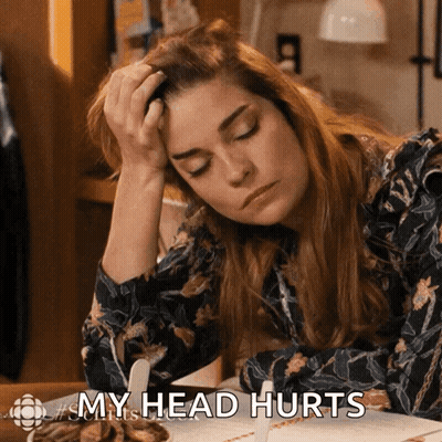 A Woman Sitting At A Table With Her Hand On Her Head And The Words My Head Hurts GIF
