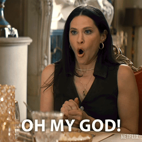 A Woman Sitting At A Table With Her Mouth Open And The Words Oh My God GIF