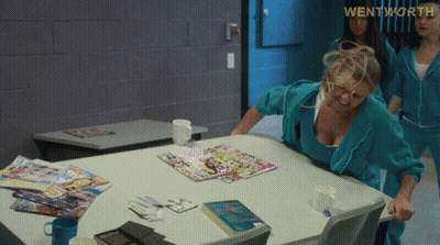 A Woman Sitting At A Table With Magazines On It And The Word Wentworth On The Bottom GIF
