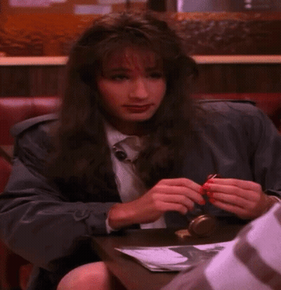 A Woman Sitting At A Table With Red Nails GIF