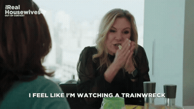 A Woman Sitting At A Table With The Words I Feel Like I 'M Watching A Trainwreck GIF