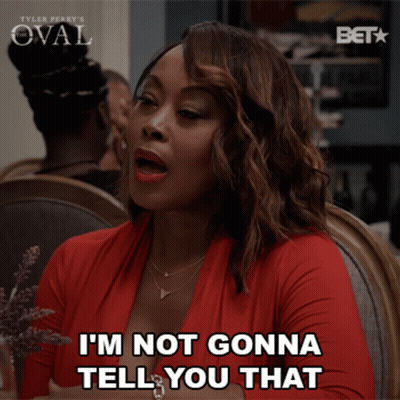 A Woman Sitting At A Table With The Words I 'M Not Gonna Tell You That GIF