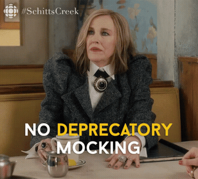 A Woman Sitting At A Table With The Words No Depredatory Mocking GIF