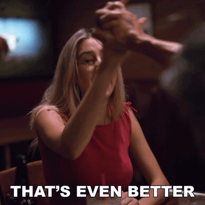 A Woman Sitting At A Table With The Words That 'S Even Better Written Below Her GIF