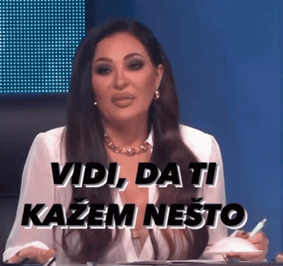 A Woman Sitting At A Table With The Words Vidi Da Ti Kazem Nešto Written On The Screen Behind Her GIF