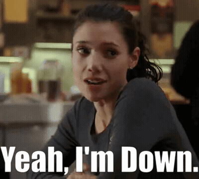 A Woman Sitting At A Table With The Words Yeah I 'M Down GIF