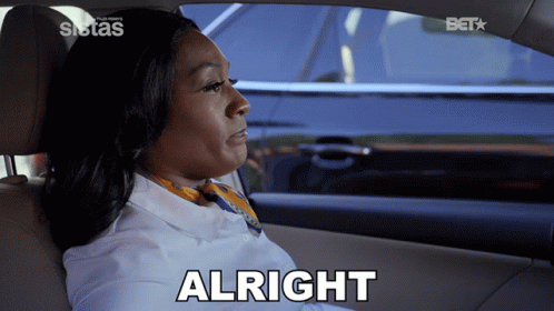 A Woman Sitting In A Car With The Word Alright On The Bottom GIF