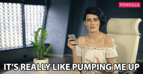 A Woman Sitting In A Chair Holding A Cell Phone With The Words " It 'S Really Like Pumping Me Up " Above Her GIF