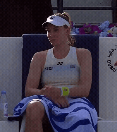 A Woman Sitting In A Chair With A Towel Around Her Waist That Says Dubai On It GIF