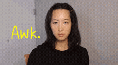 A Woman Sitting In A Chair With The Word Awk Written In Yellow GIF