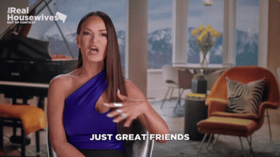 A Woman Sitting In A Chair With The Words Just Great Friends On The Screen GIF