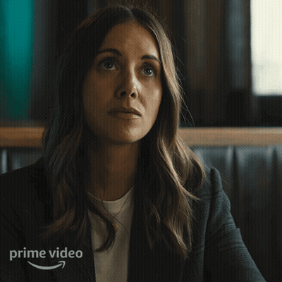A Woman Sitting In A Diner With The Word Oof Written On The Bottom GIF