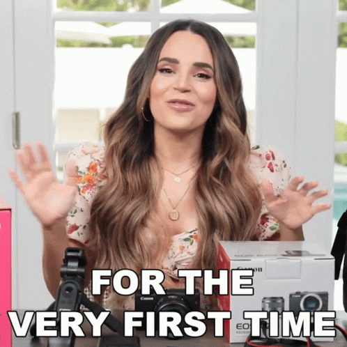 A Woman Sitting In Front Of A Camera With The Words For The Very First Time Above Her GIF