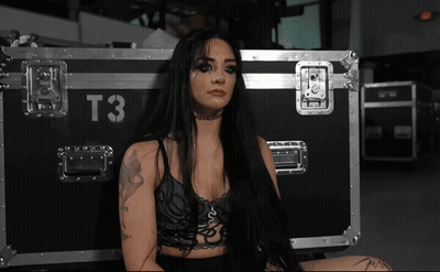 A Woman Sitting In Front Of A Case That Says T3 On It GIF