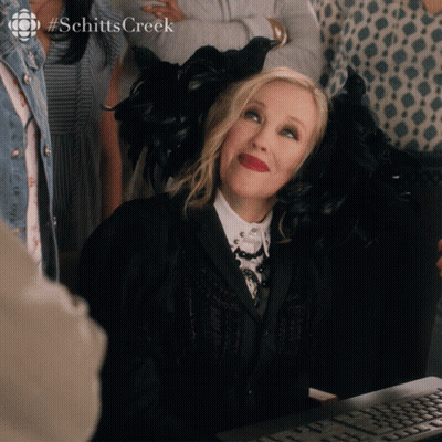 A Woman Sitting In Front Of A Computer With The Hashtag Schitts Creek On The Bottom GIF