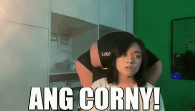 A Woman Sitting In Front Of A Green Wall With The Words Ang Corny On It GIF