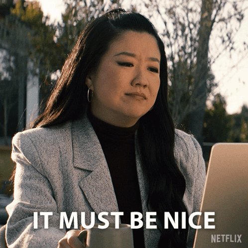 A Woman Sitting In Front Of A Laptop With The Words " It Must Be Nice " On The Bottom Right GIF