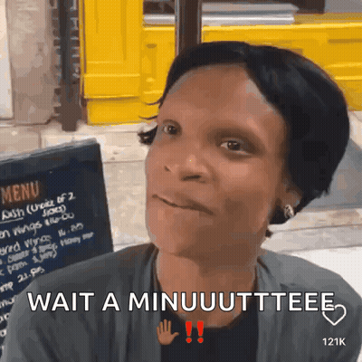 A Woman Sitting In Front Of A Menu Board Says Wait A Minuuuttee GIF