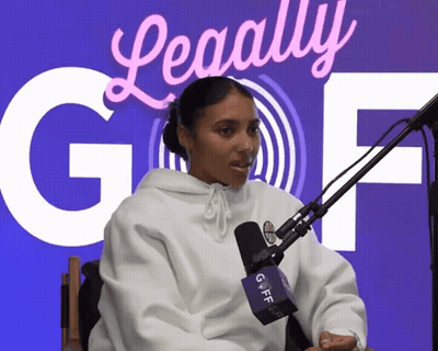 A Woman Sitting In Front Of A Microphone With A Sign Behind Her That Says ' Legally Gof ' GIF