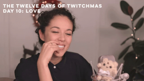A Woman Sitting In Front Of A Microphone With The Words " The Twelve Days Of Twitchmas Day 10 : Love " Above Her GIF