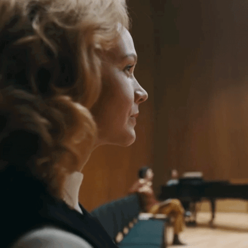 A Woman Sitting In Front Of A Piano With A Blurred Background GIF