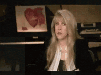 A Woman Sitting In Front Of A Piano With A Picture Of A Heart In The Background GIF