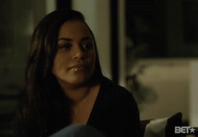 A Woman Sitting In Front Of A Sign That Says Bet On It GIF