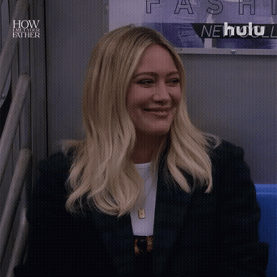 A Woman Sitting In Front Of A Sign That Says How I Met Your Father GIF