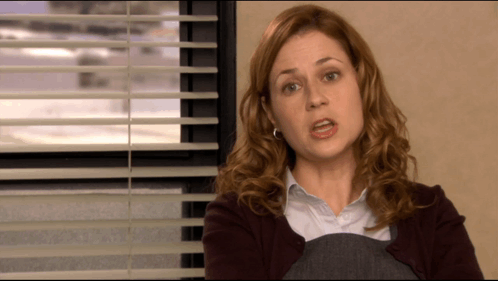 A Woman Sitting In Front Of A Window With Blinds On GIF