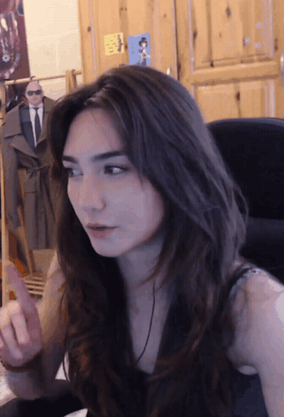 A Woman Sitting In Front Of A Wooden Door With A Sticker On It That Says ' A ' GIF