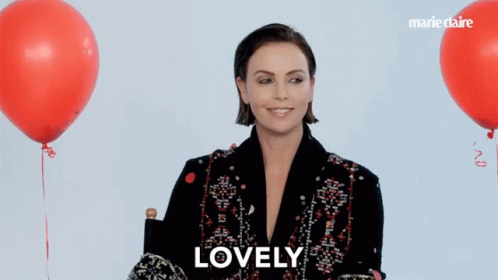 A Woman Sitting In Front Of Red Balloons With The Word Lovely On The Bottom Right GIF