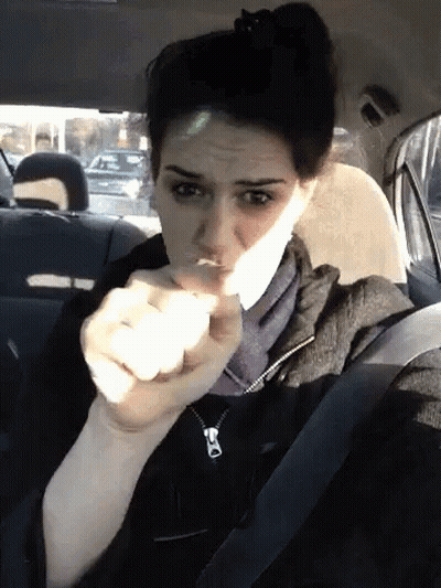 A Woman Sitting In The Back Seat Of A Car Making A Face GIF