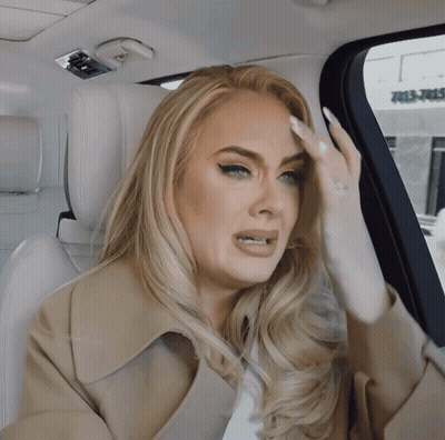 A Woman Sitting In The Back Seat Of A Car With Her Hand On Her Head GIF