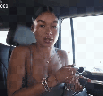 A Woman Sitting In The Back Seat Of A Car With The Number 000 On The Bottom Right GIF