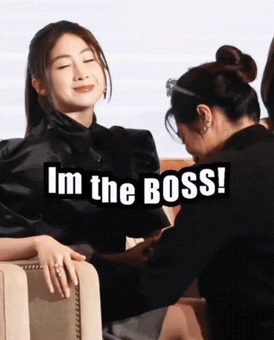 A Woman Sitting Next To Another Woman With The Words I 'M The Boss Below Her GIF