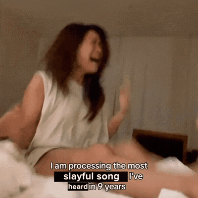 A Woman Sitting On A Bed Says I Am Processing The Most Slayful Song I 'Ve Heard In Nine Years GIF